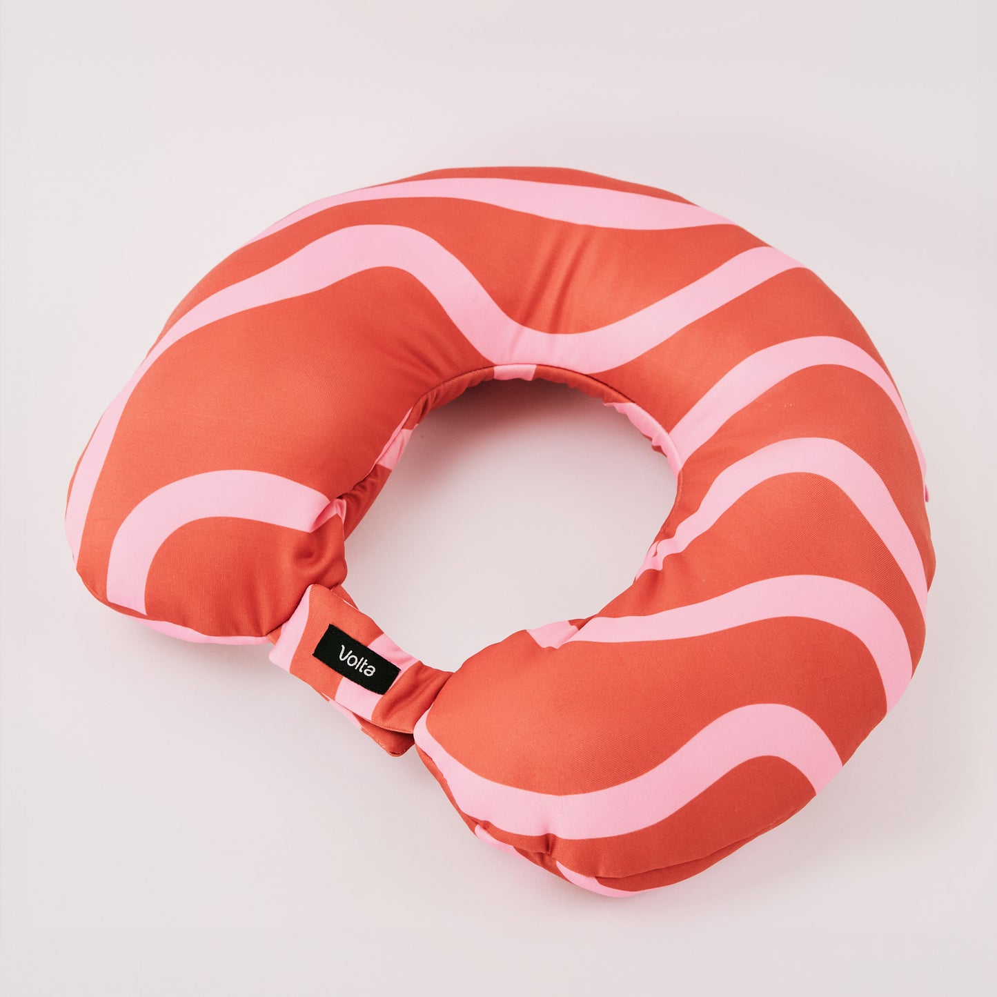 Red and pink striped travel neck pillow with a soft, compact design displayed on a clean background.